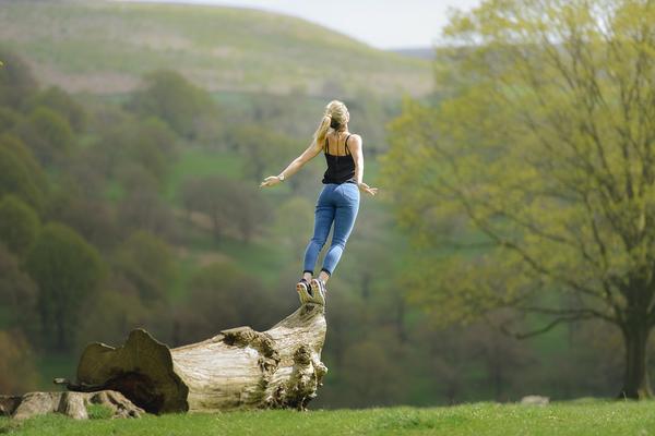 Woman on tip toes on fallen tree