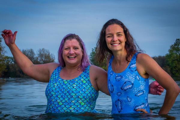 Two swimmers in river at sunrise