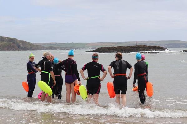 Three swimmers approaching sea on beach