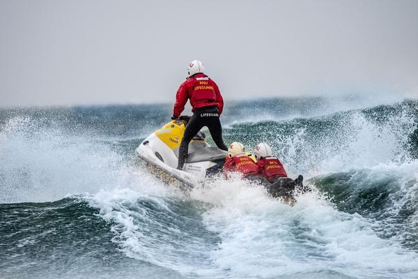 RNLI lifeguards on a jet ski speeding over breaking waves in the ocean