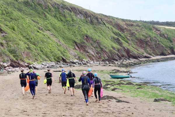 Swimmers beneath cliffs on beach