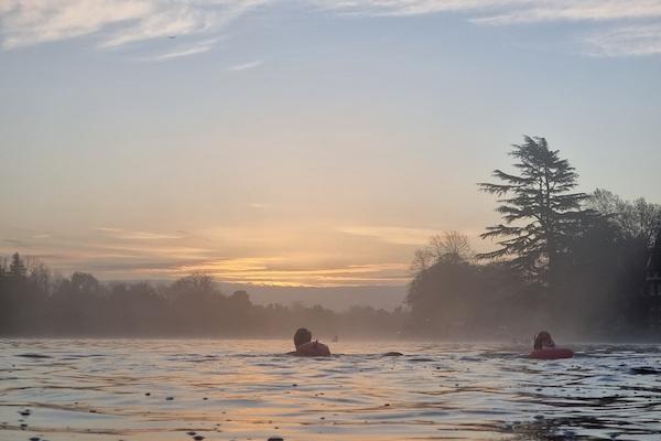 Two swimmers in river at sunrise