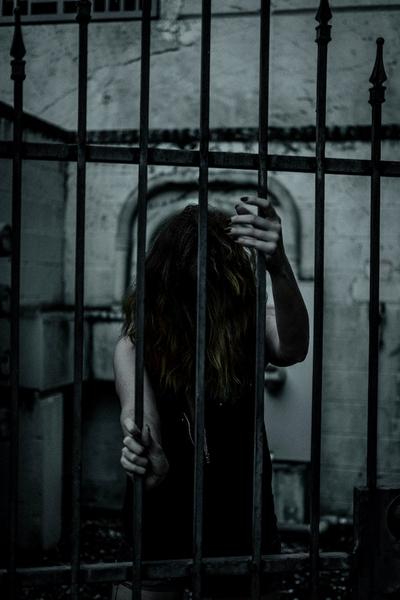 Photo by Connor  McManus: https://www.pexels.com/photo/a-woman-is-behind-bars-in-a-dark-room-15081655/