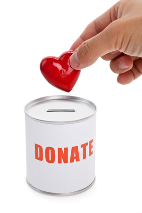 A hand putting a heart in a donation can.