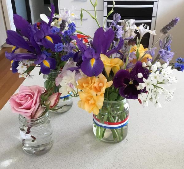 a collection of spring bloom including dutch iris, freesias, lavendar, pansies and more in glass jars.
