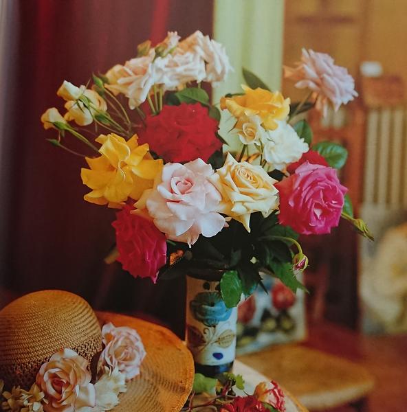 Arrangement of various coloured roses and a straw hat with roses