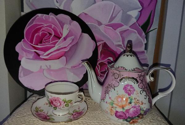 Teapot and teacup infront of a pink rose painting