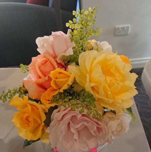 An arrangment of yellow and pink roses with maidenhair fern