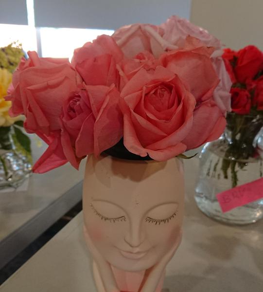 And arrangment of pink roses in a vase with a face on it