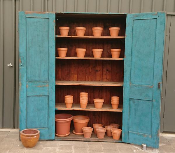 Cupboard with turquoise doors and terracotta pots on shelves