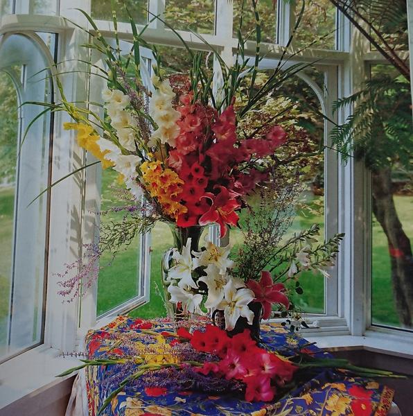 Arrangement of gladioli and oriental lilies in a conservatory window.