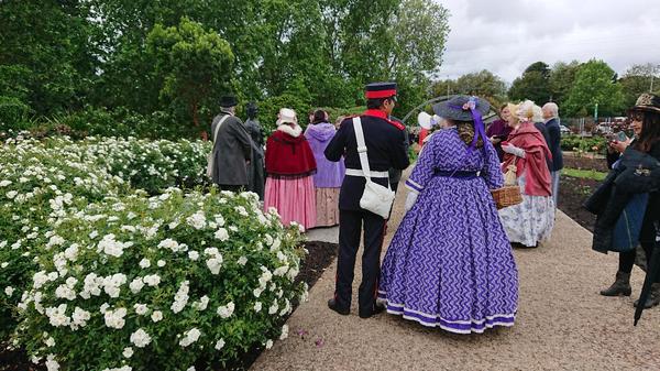 People i historical costumes in rose garden