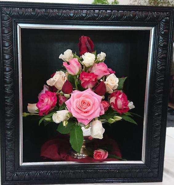 Arrangement of pink, white and red roses in a black picture frame