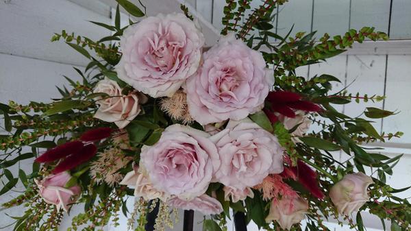 A florist arrangement of pale mauve roses and burgundy and green foliage.