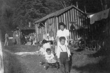 Fumiko Fukuhara with two of her children in front of their tarpaper shack near Tappin B.C. Photo by George Fukuhara