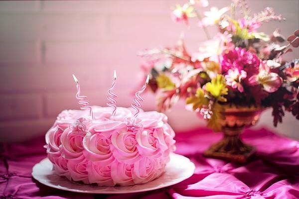 image of a pink cake with candles and icing roses
