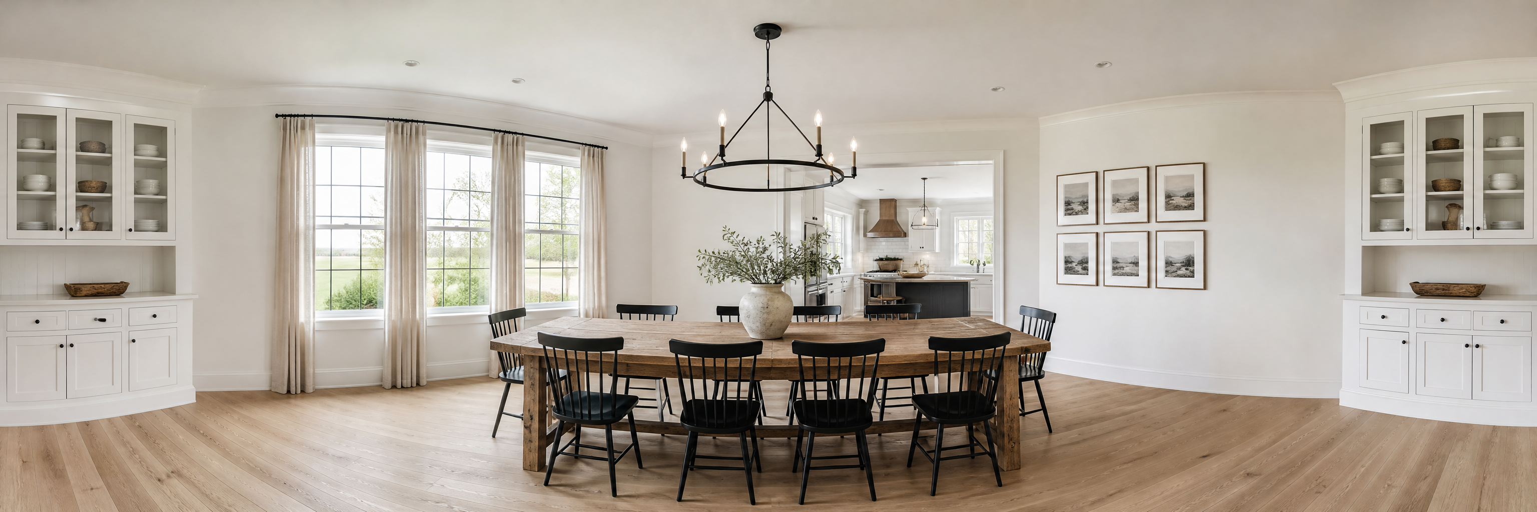 360 degree view of a dining room with a long oak table, black chairs and an iron chandelier