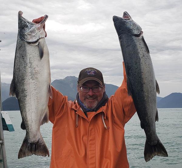 Hank holding up two coho salmon in Alaska.