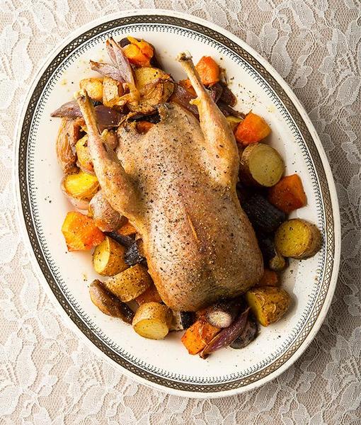 Roast grouse with root vegetables on a platter. 