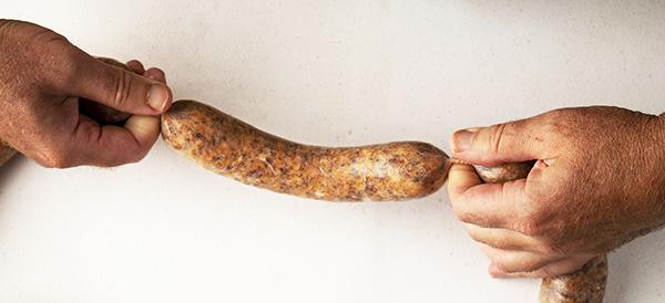 Hands forming a link of homemade sausage