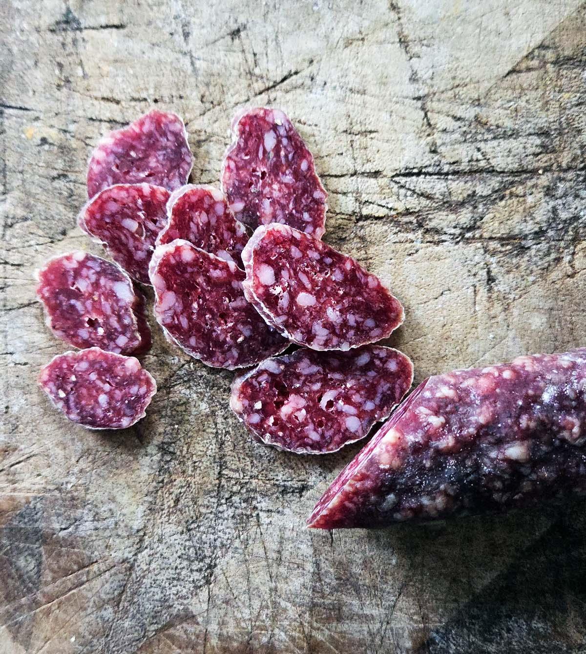 Wild boar salami on a weathered cutting board.