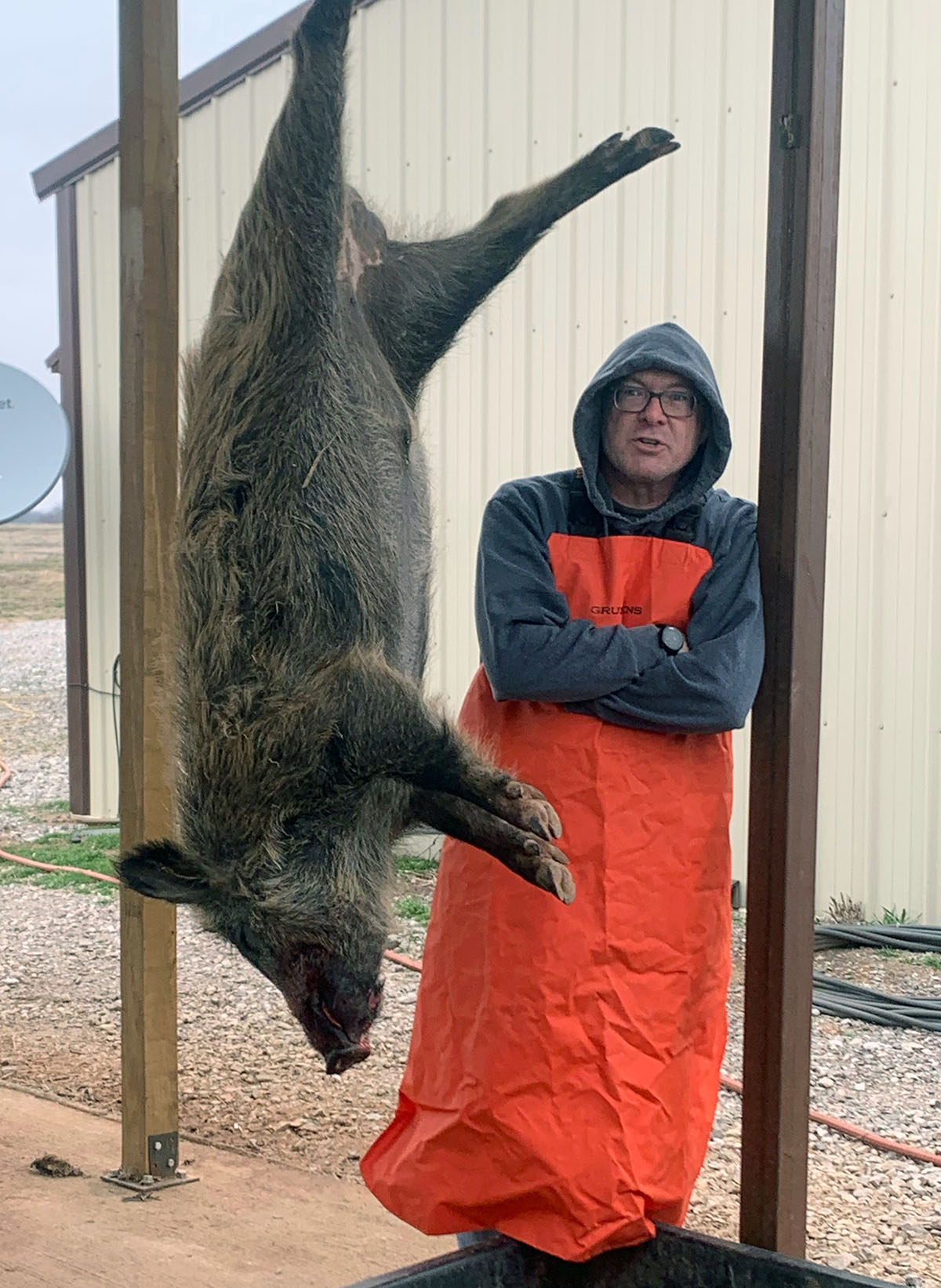 Hank standing in butchering gear next to a wild hog. 