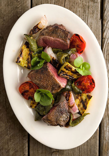 Grilled duck breast with vegetables on a platter. 