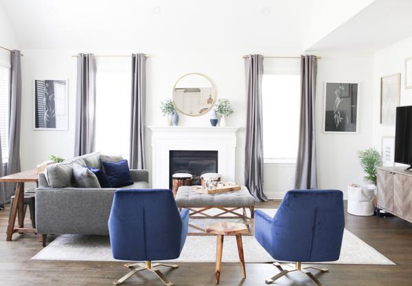 A bright room with wood table, blue and gold chairs, and a grey couch.