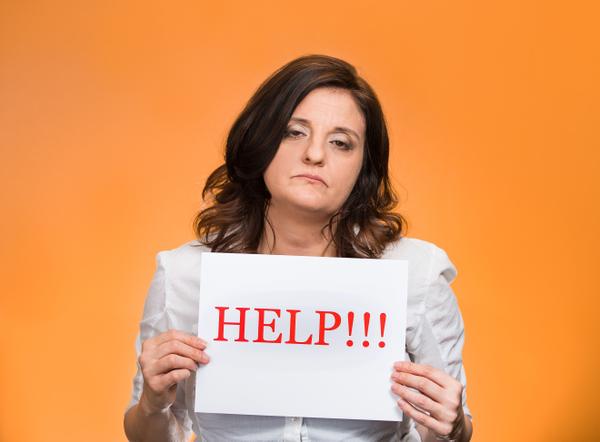 Woman looking stressed holding a HELP sign
