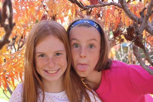 Two girls posing for the camera (one is smiling, the other one is sticking her tongue out)