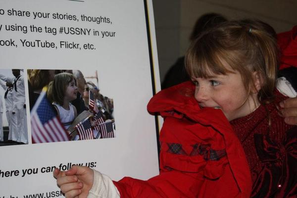 Little girl looking at a picture of herself in between American flags