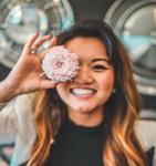 A woman being silly and holding a donut over her eye