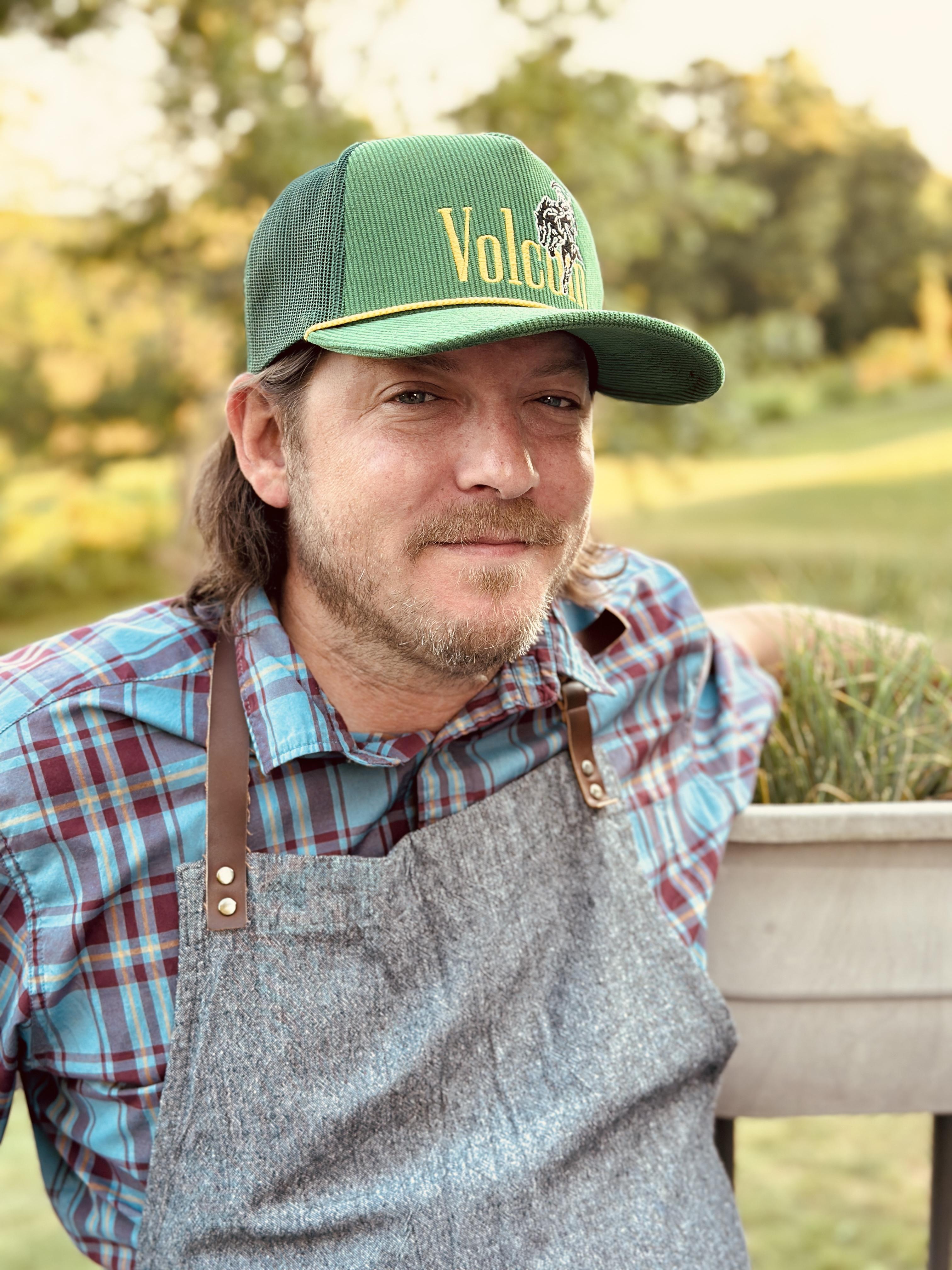 Chef Sterling Reitzel, a private chef in Bucks County, wearing an apron outdoors at golden hour