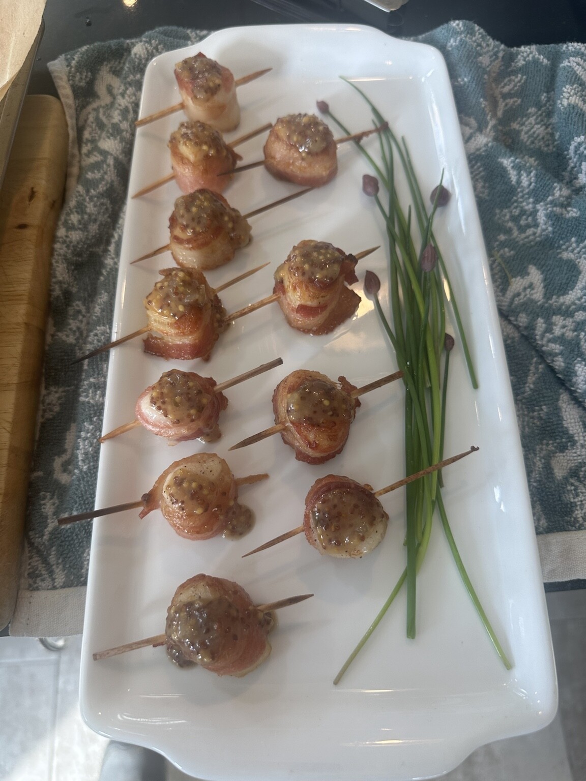 Bacon-wrapped scallops with whole grain mustard sauce and fresh chives, served as passed hors d'oeuvres at a private event
