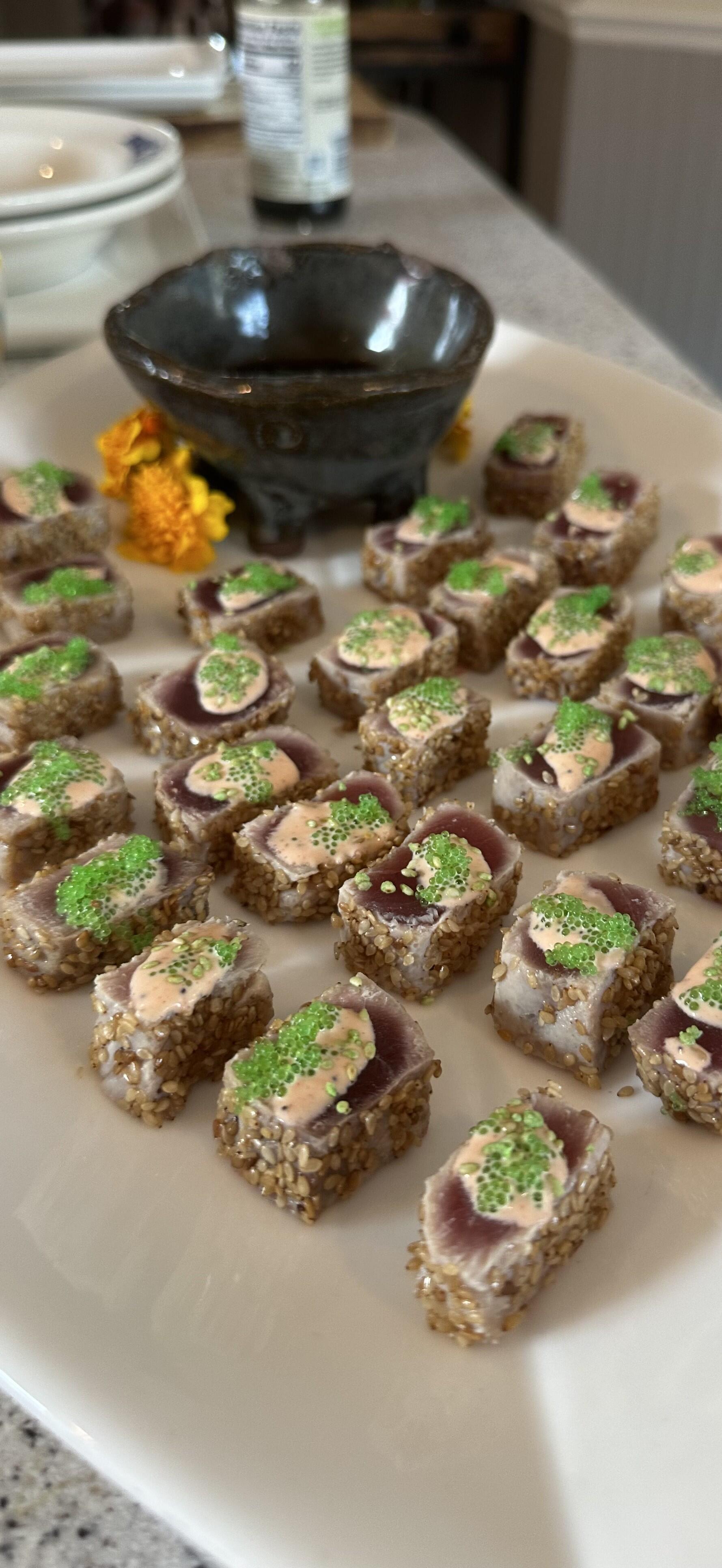 Sesame-crusted seared tuna bites with spicy aioli and green tobiko, arranged on a platter
