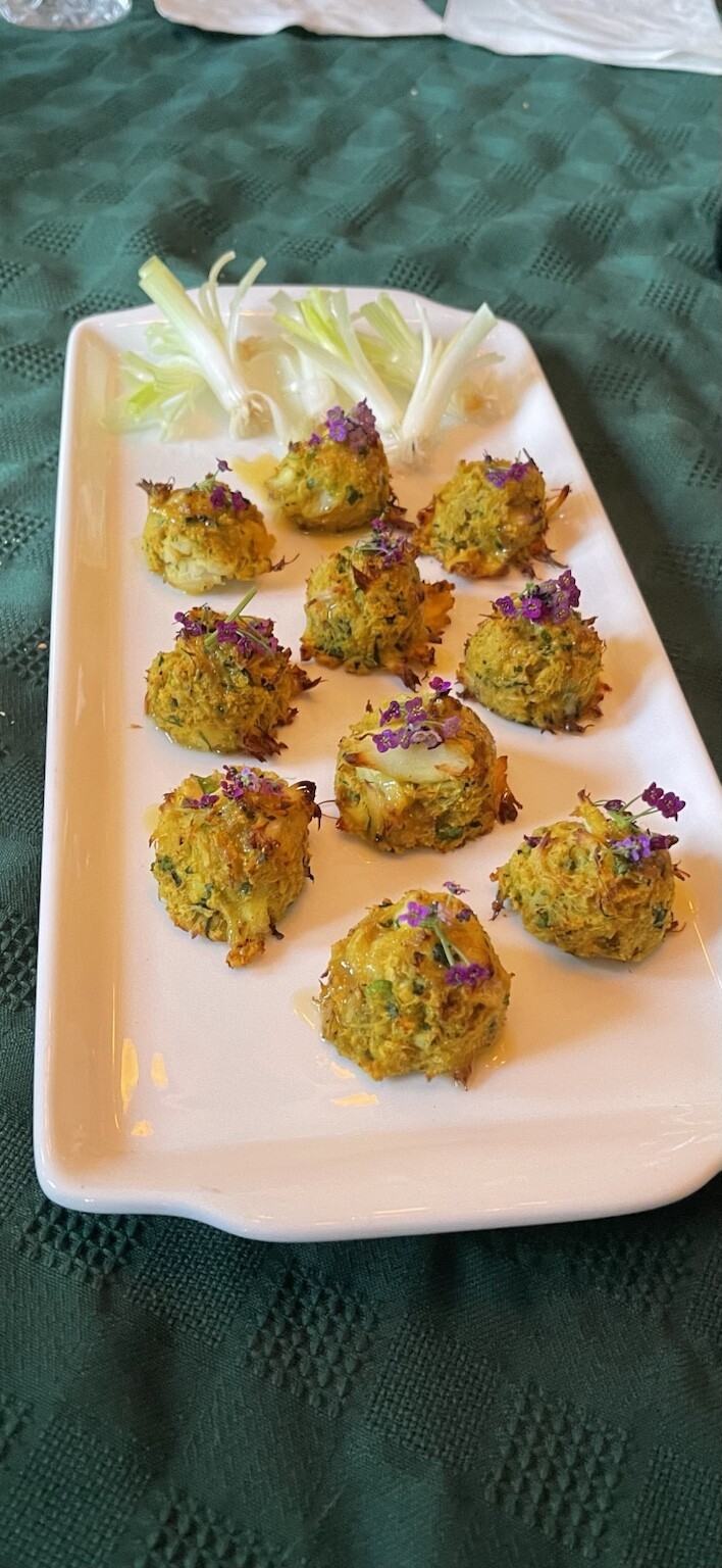 Golden crab cakes topped with edible flowers, served as passed hors d'oeuvres at a private event