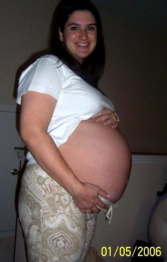Amber pregnant with one of her babies, smiling and holding her belly