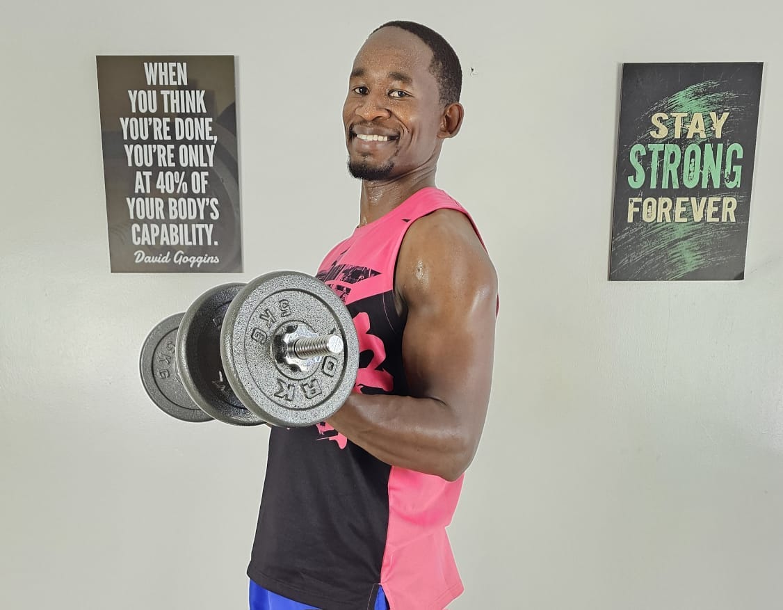 Coach Brian Syuki holding a dumbbell in his gym