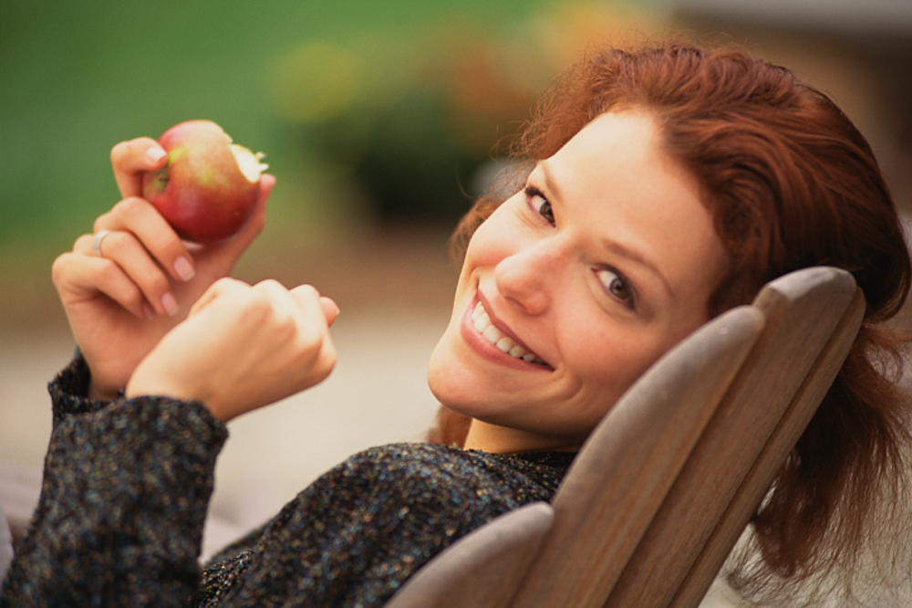 a woman smiling holding an apple