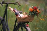 Bicycle basket with flowers, wine and french bread