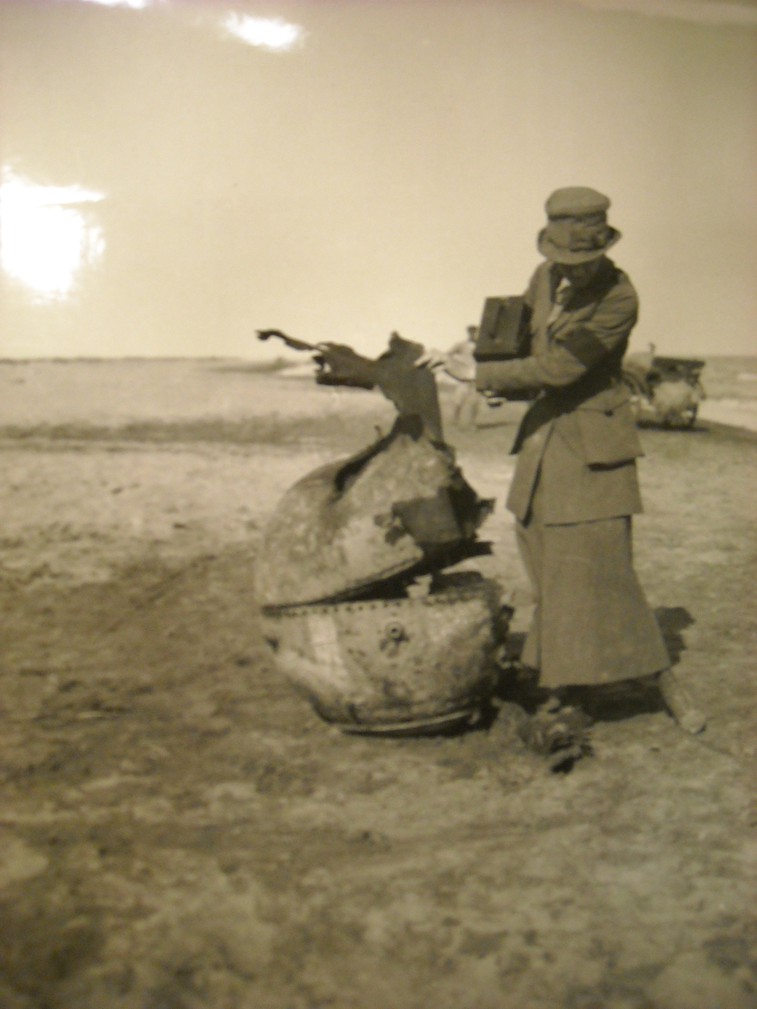 Photojournalist Helen Jones Kirtland looking at a spent landmine, probably near Ypres, Belgium,1919.