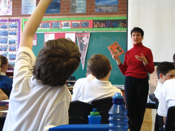 Boys in classroom engaging in conversation about a book