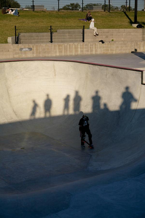 Image - skater in dark bowl, shadows of observers, others on the grass, Lee & Joe Jamail Skatepark, Houston, Texas © Heidi Straube 2013